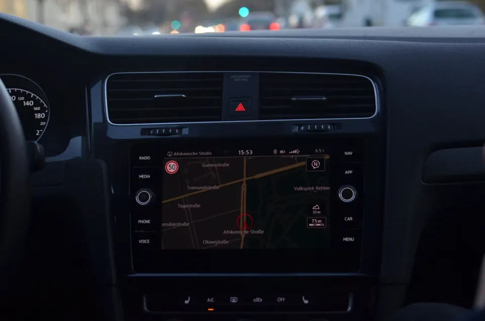 Car dashboard screen showing a navigation map with the vehicle's position, traffic ahead through the windscreen